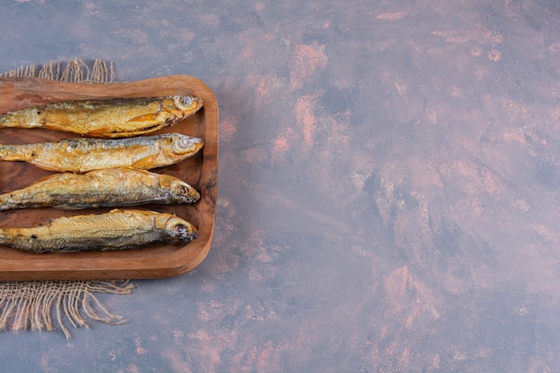 Bezpłatne zdjęcie pokrojone cytryny i soloną rybę na desce do krojenia na jutowej serwetce, na marmurowej powierzchni