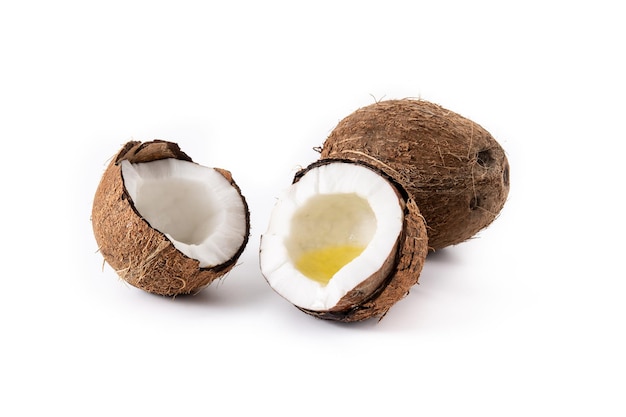 pokrojone orzechy kokosowe z olejem w środku na białym tle