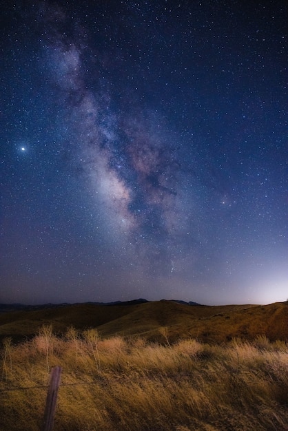 Pole brązowej trawy pod błękitnym niebem w porze nocnej