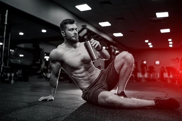 Półnagi muskularny mężczyzna po odpoczynku po ciężkim treningu. silny sportowiec męski trening w siłowni.