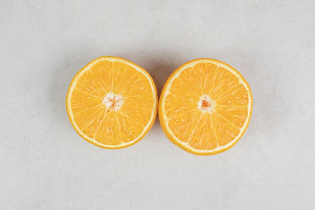 Połówki soczystej pomarańczy na szarej powierzchni.