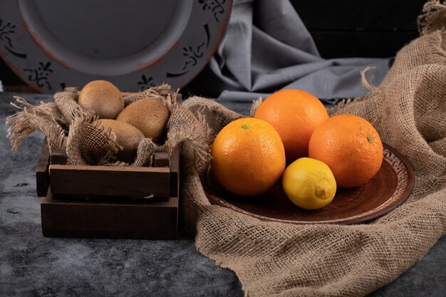 Bezpłatne zdjęcie pomarańcza i kiwi w ciemnej, rustykalnej przestrzeni.