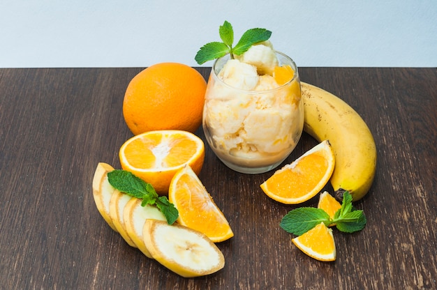 Pomarańcza; lody bananowe na drewniane teksturowane tło na niebieskim tle