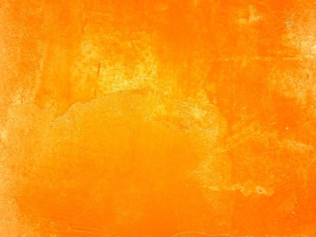 Pomarańczowa ściana z pęknięciami i łuszczącą się farbą.
