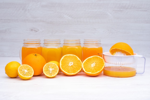 pomarańczowy sok owocowy w szklankach w pobliżu sokowirówki na białej powierzchni