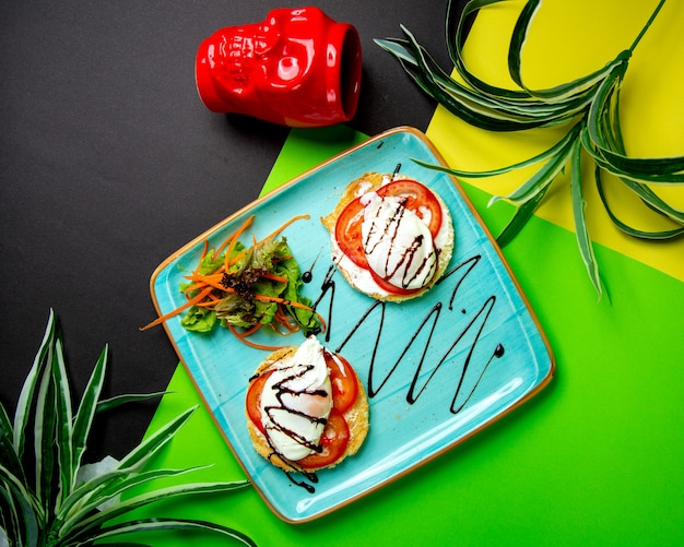 Bezpłatne zdjęcie pomidor i mozzarella umieszczone na okrągłym toście podawane z zieloną sałatą