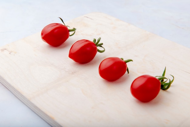 Pomidory na tnącej desce na bielu ukazują się bocznego widok