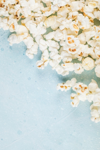 Popcorny rozłożone na niebieskim stole z prawego rogu