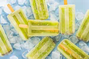 Bezpłatne zdjęcie popsicle lody kiwi na tle deska drewniana