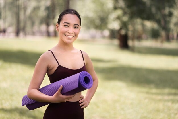 Portret aktywnej kobiety mienia joga mata