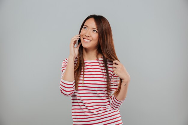 Portret atrakcyjna azjatykcia dziewczyna opowiada na telefonie komórkowym
