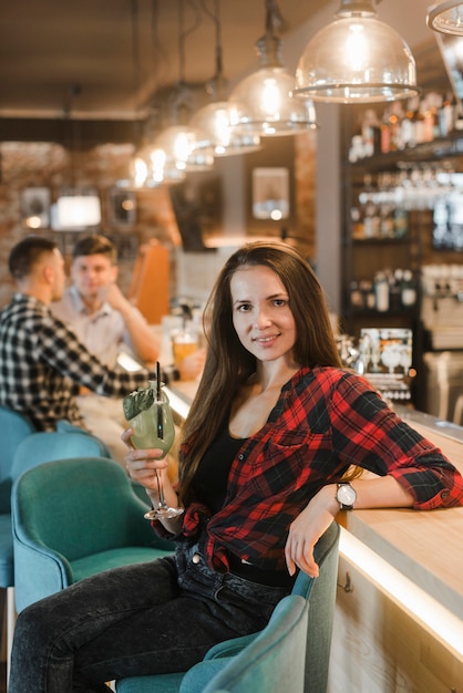 Portret atrakcyjna młoda kobieta siedzi blisko baru kontuaru mienia koktajlu
