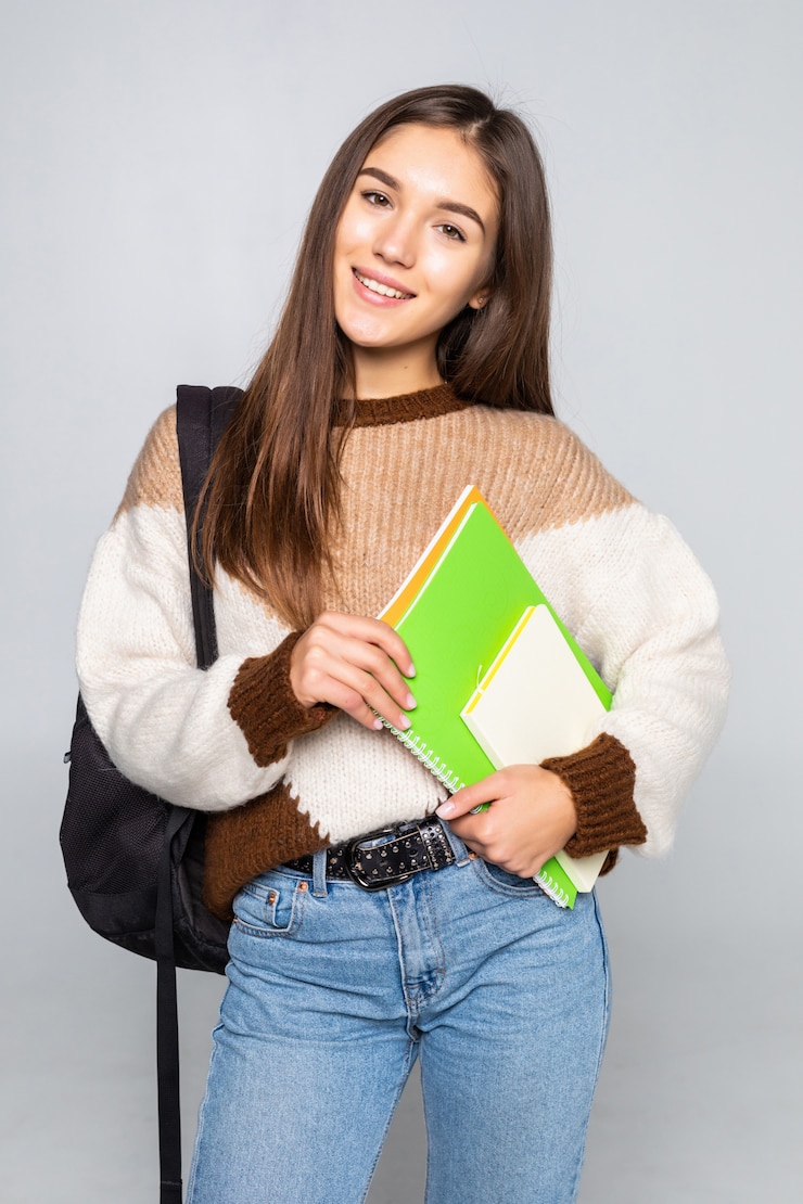 Bezpłatny plik Zdjęcie portret atrakcyjna śliczna młoda studencka dziewczyna odizolowywająca na biel ścianie