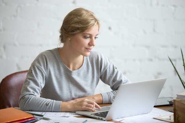 Portret atrakcyjne dziewczynka studenta przy biurku z laptopem