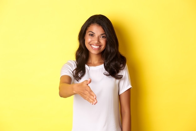 Portret atrakcyjnej afrykańskiej dziewczyny uśmiechającej się wyciągającej rękę na powitanie uścisku dłoni