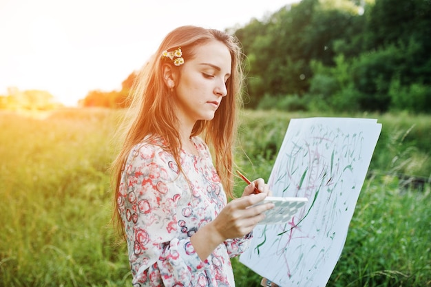 Portret atrakcyjnej młodej kobiety w długiej sukni malarskiej z akwarelą w naturze