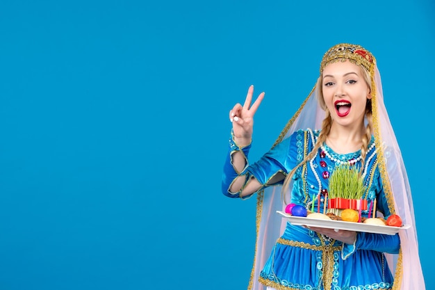 Bezpłatne zdjęcie portret azerskiej kobiety w tradycyjnym stroju z novruz xonca niebieskim tle wiosna kolor etniczna tancerka pieniędzy