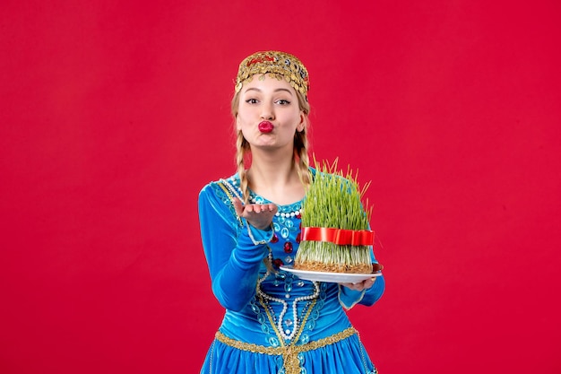 Bezpłatne zdjęcie portret azerskiej kobiety w tradycyjnym stroju z semeni studio strzał czerwone tło wiosna etniczne novruz