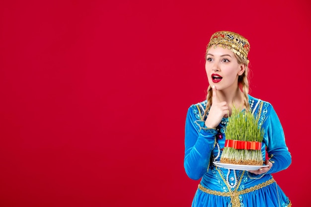 Portret azerskiej kobiety w tradycyjnym stroju z zielonym nasieniem na czerwonym tle etniczna koncepcja tancerz wiosna novruz