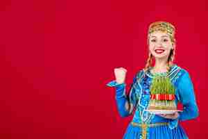 Bezpłatne zdjęcie portret azerskiej kobiety w tradycyjnym stroju z zielonym semeni studio strzał na czerwonym tle etnicznej wiosny