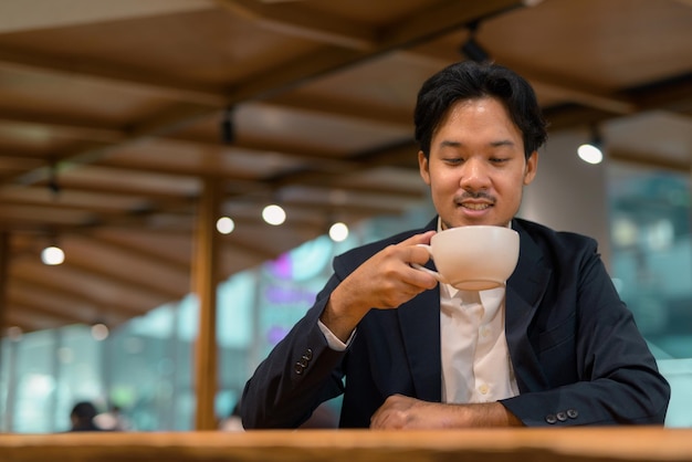 Portret Azjatyckiego Biznesmena W Kawiarni Pije Kawę Premium Zdjęcia