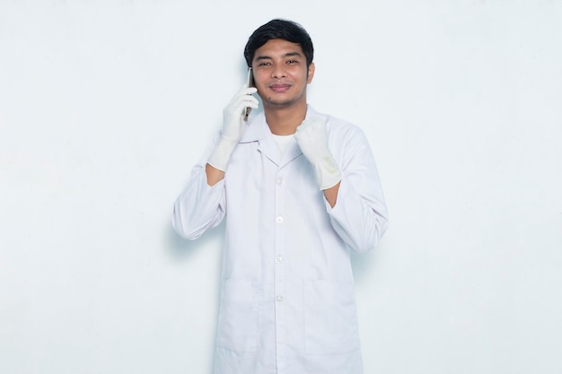 Portret azjatyckiego lekarza medycyny używającego telefonu komórkowego na białym tle