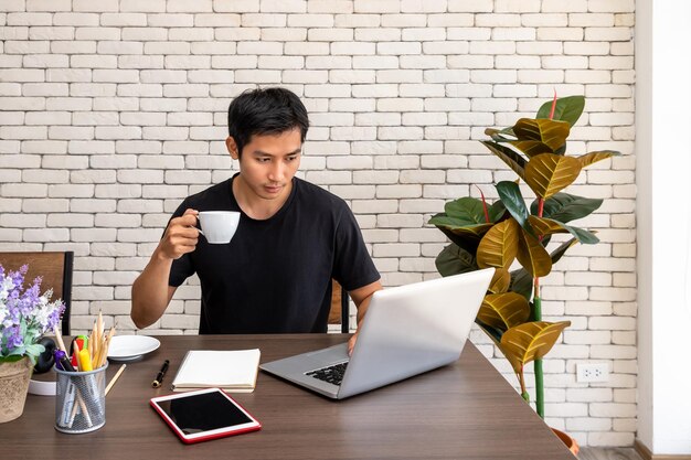 Portret azjatyckiego mężczyzny, freelancera, pracującego w domu, siedzącego przy biurku przy stole w salonie