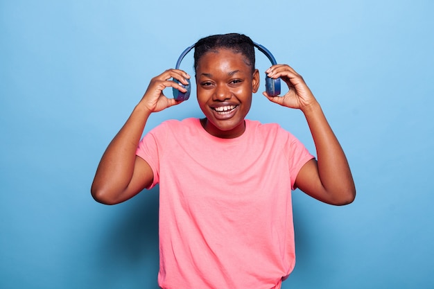 Portret beztroskiej afroamerykańskiej młodej kobiety zakładającej słuchawki