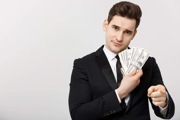 Portret biznesmena pokazujący pieniądze i wskazujący palce odizolowywających nad białym tłem