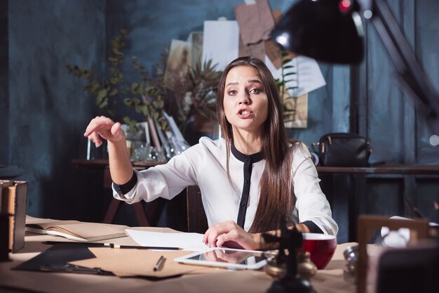 Portret bizneswoman, która pracuje w biurze i sprawdza szczegóły nadchodzącego spotkania w swoim notatniku oraz pracuje w studio na poddaszu.