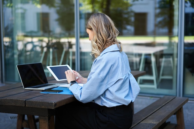Portret bizneswoman pracującej na cyfrowym tablecie sprawdzającym diagramy, siedzącej na świeżym powietrzu na świeżym powietrzu