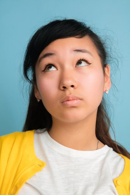 Portret bliska azjatyckich nastolatek na białym tle na niebieskiej przestrzeni