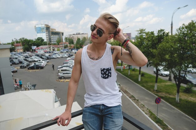 Bezpłatne zdjęcie portret blond hipster chłopiec z tatuażami i stylowe włosy