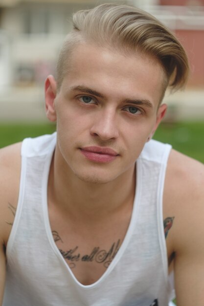 Portret blond hipster chłopiec z tatuażami i stylowe włosy