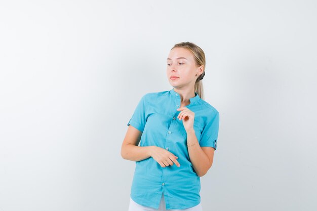 Portret blond kobieta pozuje, patrząc na bok w niebieskiej bluzce na białym tle