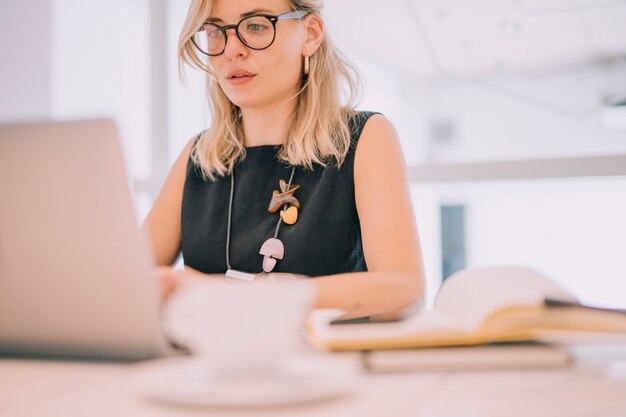 Portret blondynka młody bizneswoman patrzeje laptop w biurze