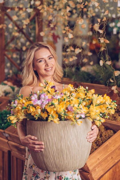 Portret blondynki uśmiechnięta młoda kobieta trzyma wielkiego garnek w żółtych kwiatach