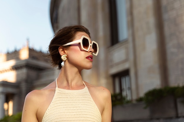 Portret bogatej kobiety na zewnątrz w stylowej sukience i okularach przeciwsłonecznych
