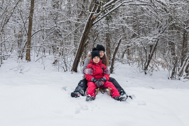 Portret brata i siostry obsiadanie na drewnianym saneczku w śnieżnym krajobrazie