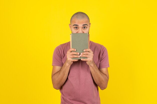 Portret brodaty mężczyzna pokazuje okładkę książki nad żółtą ścianą.