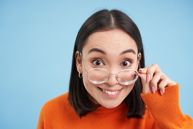 Portret Brunetki Japonki W Okularach Uśmiechającej Się I Patrzącej Z Szczęśliwą Twarzą Na Kamerę Próbuje P