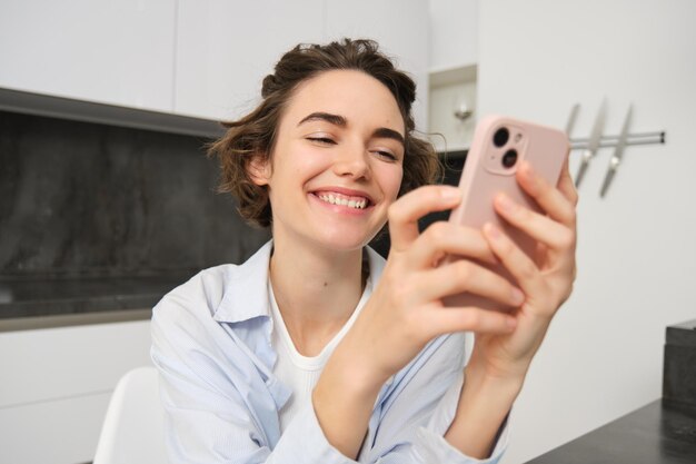 Portret brunetki rozmawiającej na telefonie komórkowym używa aplikacji smartfonowej z domu zamówień dostawy podczas