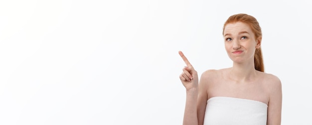 Bezpłatne zdjęcie portret caucasian ładny w trosce i szoku wskazuje palec wskazujący na bok na białym tle