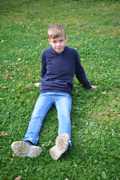 Portret Chłopca Na Zewnątrz Odpoczywającego Na Trawniku Premium Zdjęcia