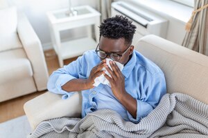 Portret chorego z alergią na grypę, kaszel, kaszel chory człowiek z bólem głowy, siedzący pod kocem, z wysoką gorączką i grypą, odpoczywający i pijący gorący napój