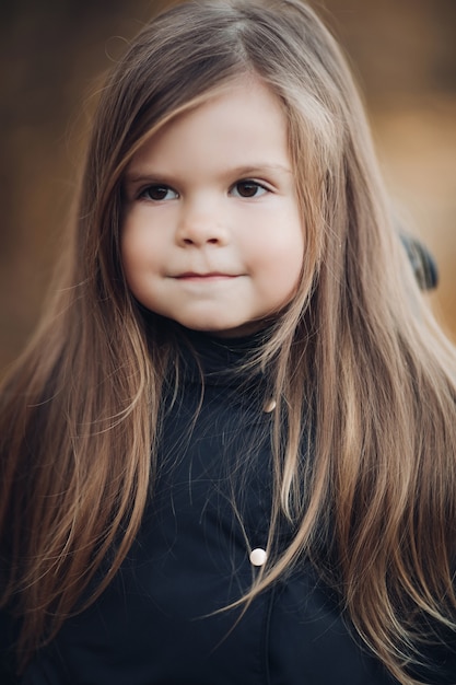 Portret cute dziewczynka z długimi włosami i piwne oczy średni z bliska. Urocza twarz kobiecego dziecka o doskonałej skórze i naturalnym pięknie z emocjami spokoju