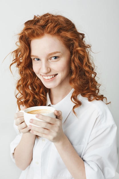 Portret czuła rudzielec dziewczyna uśmiecha się trzymający filiżankę z piegami