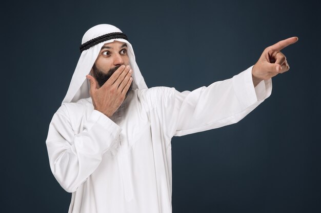 Portret do połowy długości arabski saudyjski biznesmen. Młody model mężczyzna zdziwiony, wskazując lub wybierając. Pojęcie biznesu, finanse, wyraz twarzy, ludzkie emocje.