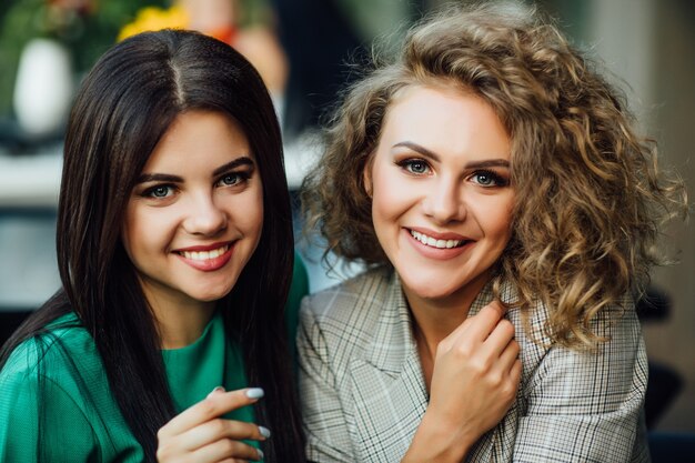 Portret dwóch młodych i uroczych sióstr uśmiechniętych, zabawny weekend spędzony w kawiarni razem.