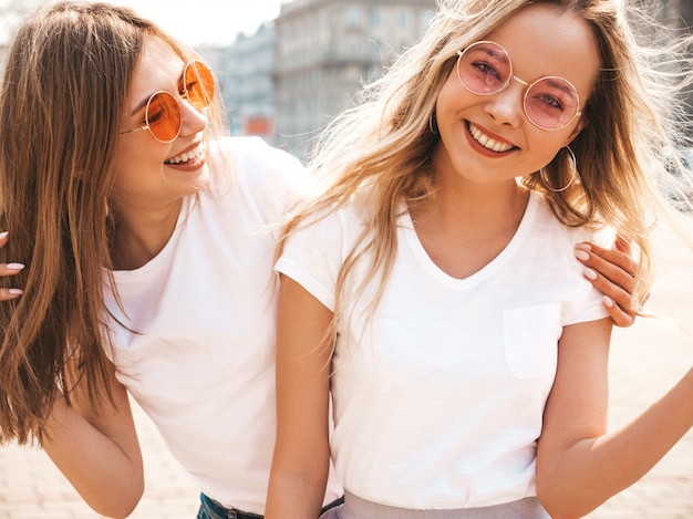 Bezpłatne zdjęcie portret dwóch młodych pięknych blond uśmiechnięte dziewczyny hipster w modne letnie białe ubrania t-shirt. .